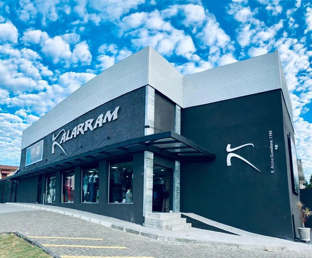 Fachada da loja Kalarram: prédio grafite com o nome Kalarram e o símbolo da marca em branco, na Rua Alcino Guanabara, 1796, no Hauer, em Curitiba.